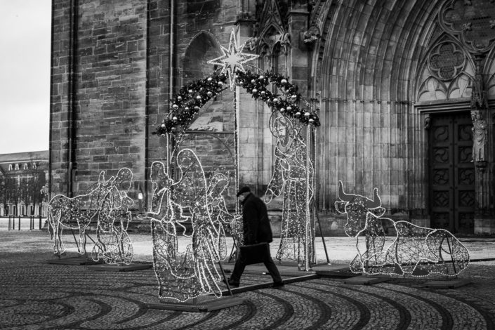 Ein Mann geht offenbar schnellen Schrittes durch die Krippenfiguren der Lichterwelt vor dem Magdeburger Dom