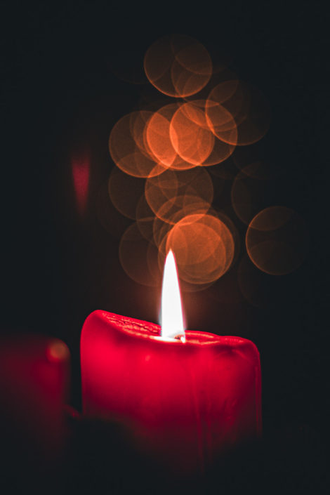 Rote Kerze vor dunklem Hintergrund mit Bokeh