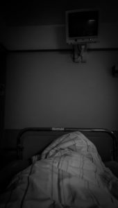 Krankenhausbett aus der Perspektive der im Bett liegenden mit Monitor gegenüber vom Bett