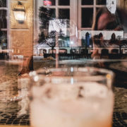 Durch ein Wintergartenfenster fotografierte Gnadenkappel auf dem Kapellplatz in Altötting, im Vordergrund ein Weizenbierglas, Spiegelungen im Fenster